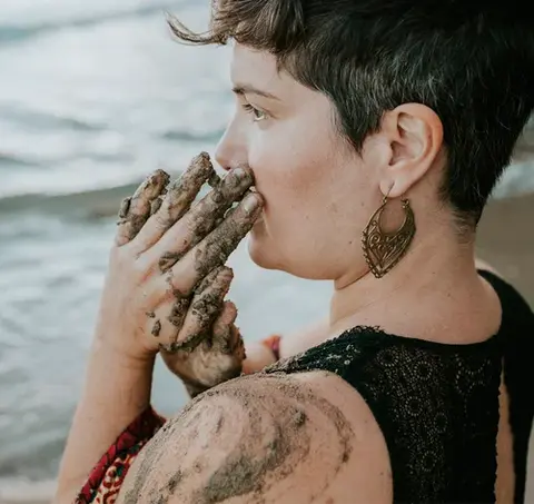 Miriam Erre con las manos cubiertas de arena, en actitud de recogimiento